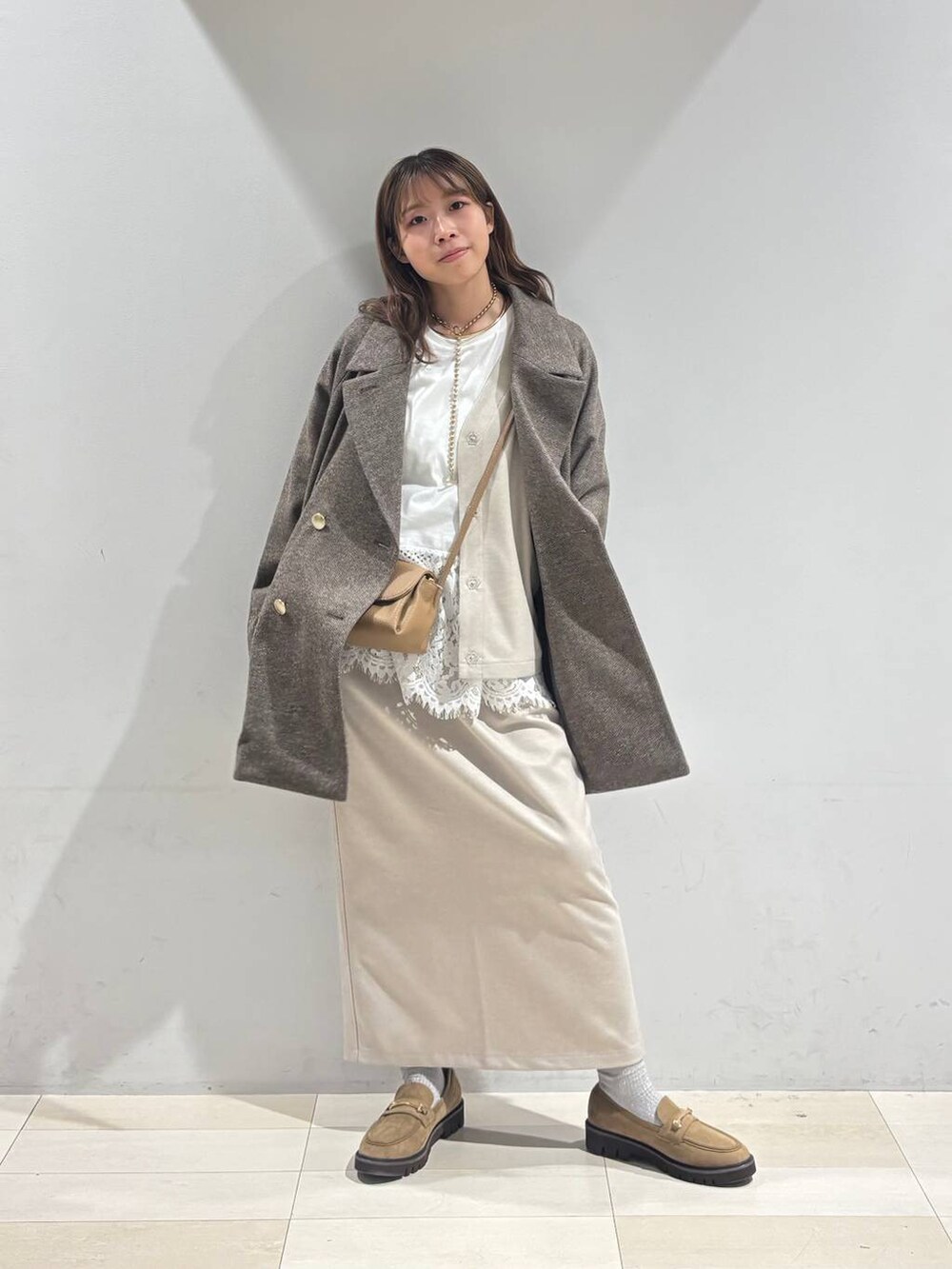 ブラウン系のチェスターコート、ベージュ系のローファー、ベージュ系のショルダーバッグを着用したレディースの秋コーディネートの5枚目の写真