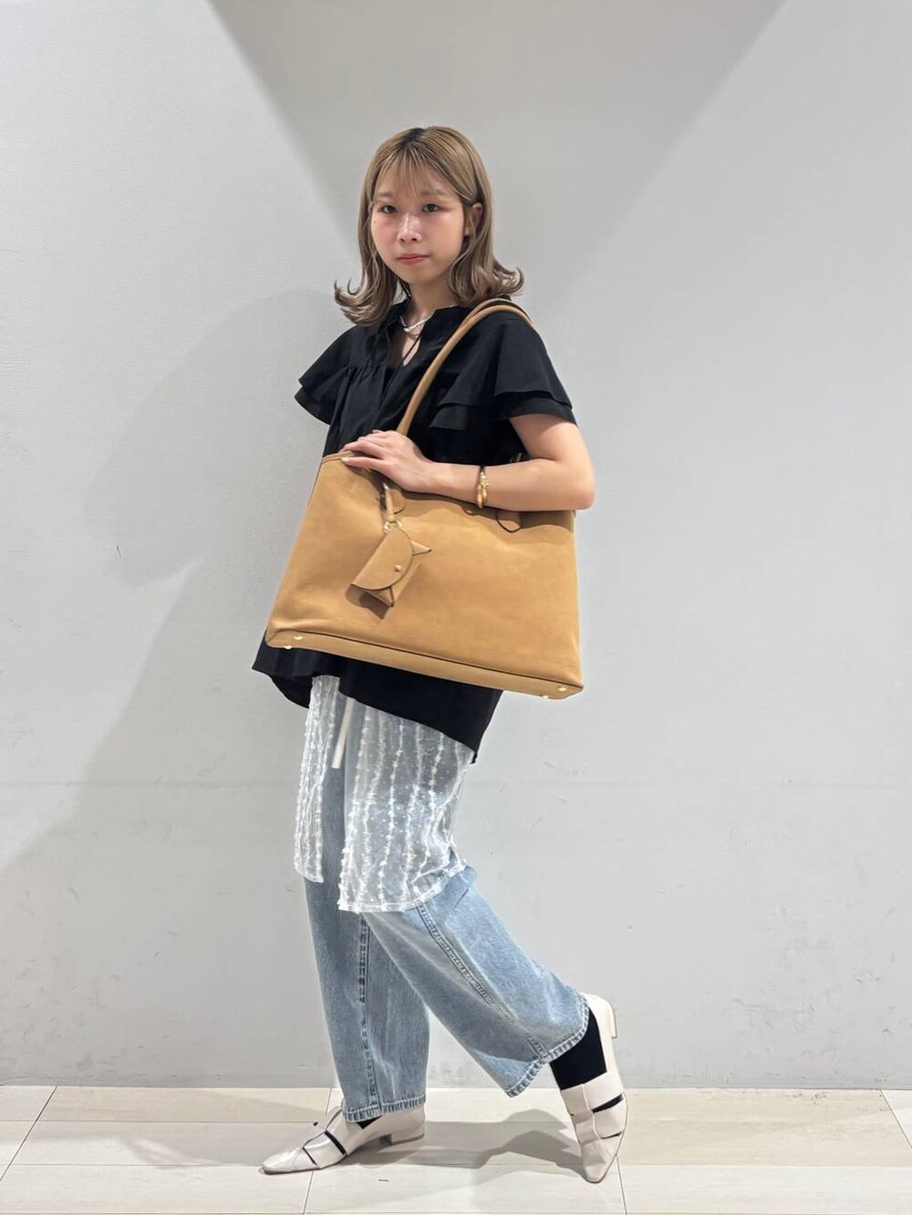 ブルー系のデニムパンツ、ホワイト系のパンプス、ベージュ系のトートバッグを着用したレディースの夏コーディネートの3枚目の写真