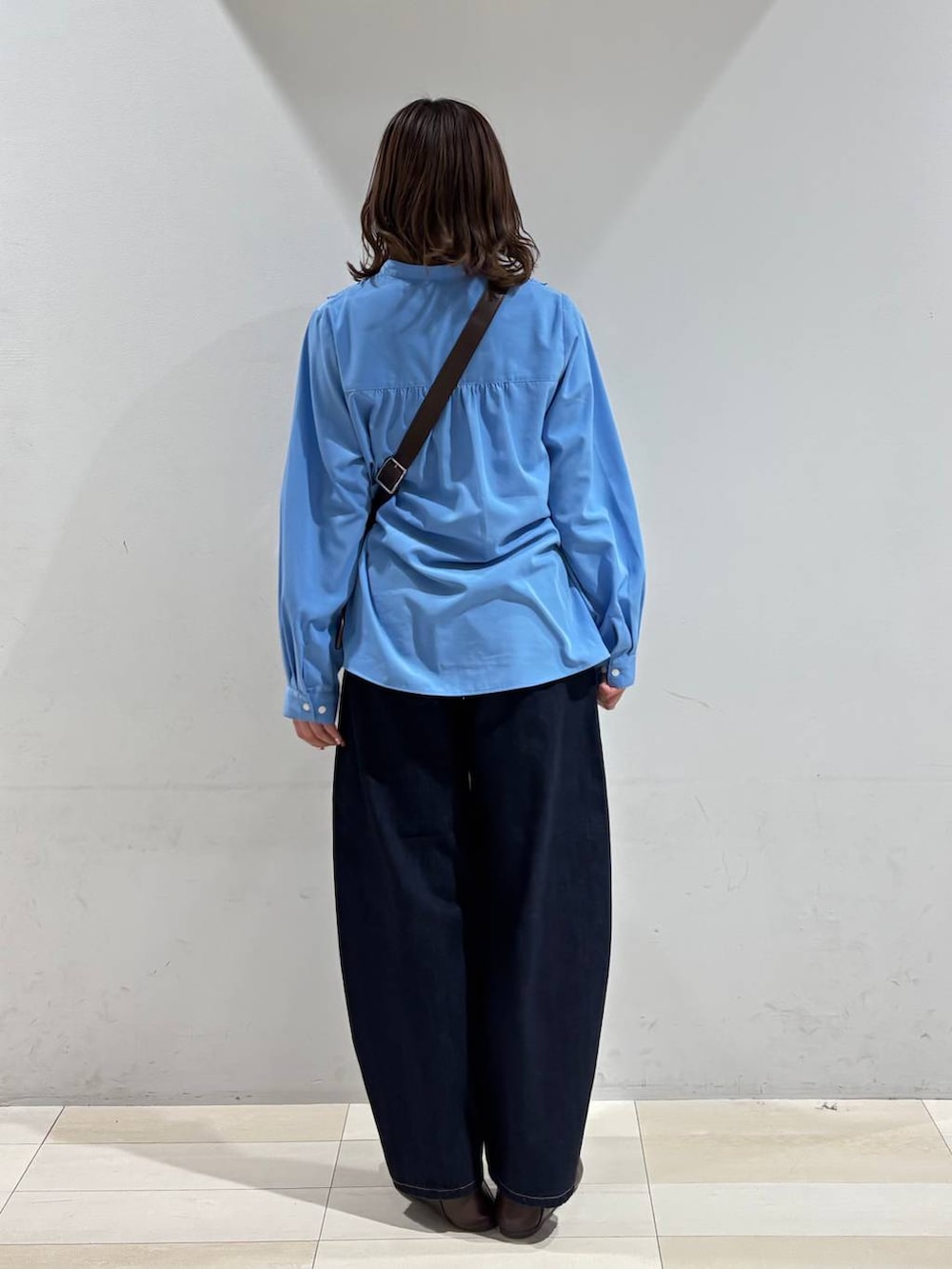 ブルー系のデニムパンツ、ブラウン系のショルダーバッグ、ブルー系のシャツ/ブラウスを着用したレディースの春コーディネートの5枚目の写真