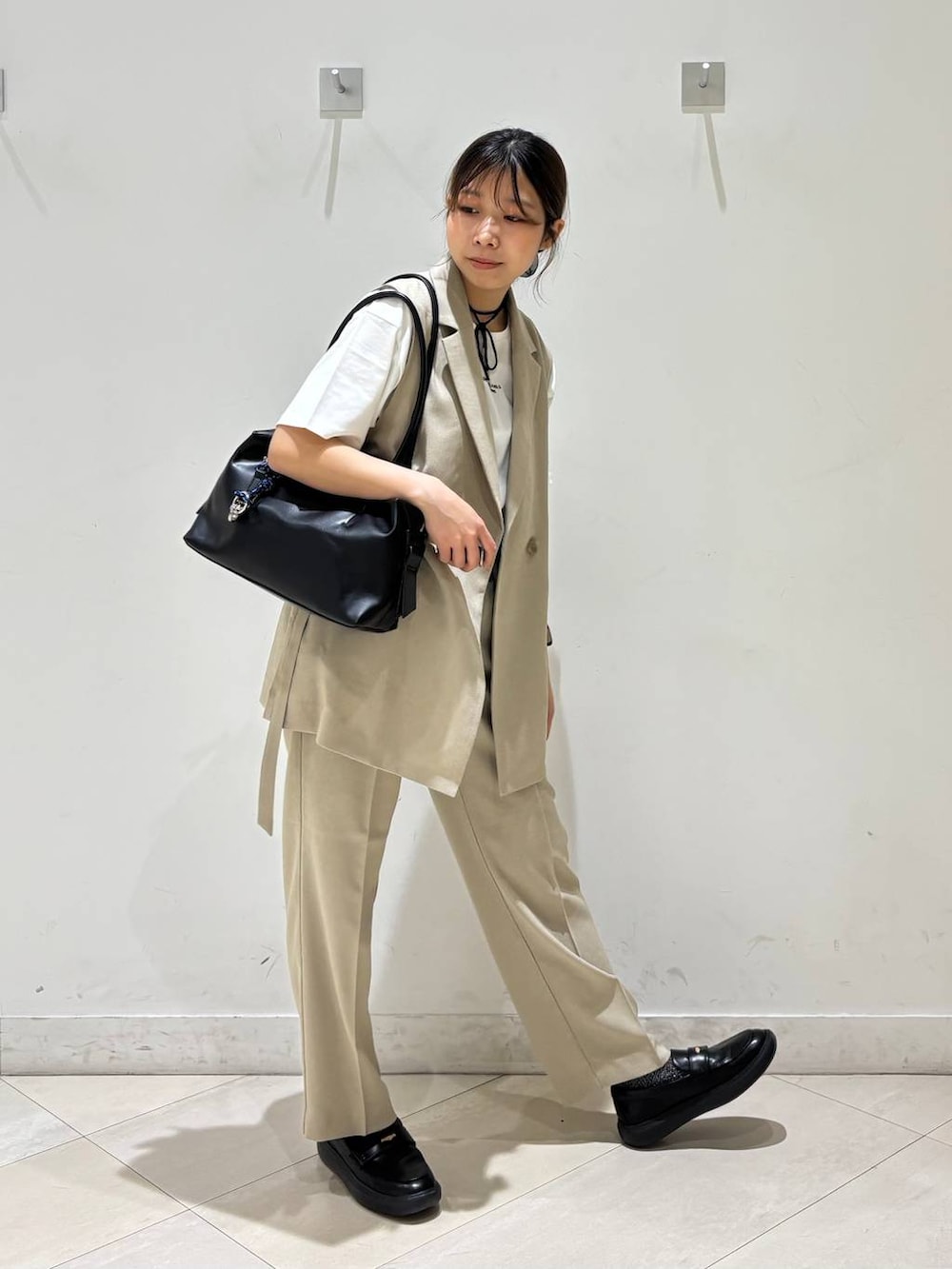 ブラック系のボストンバッグ、ベージュ系のその他パンツ、ベージュ系のベストを着用したレディースの春コーディネートの3枚目の写真