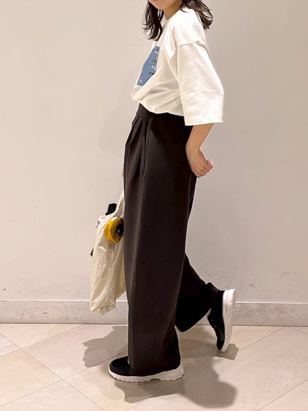 ブラック系のスニーカー、ブラウン系のその他パンツ、ホワイト系のエコバッグ/サブバッグを着用したレディースの春コーディネートの4枚目の写真