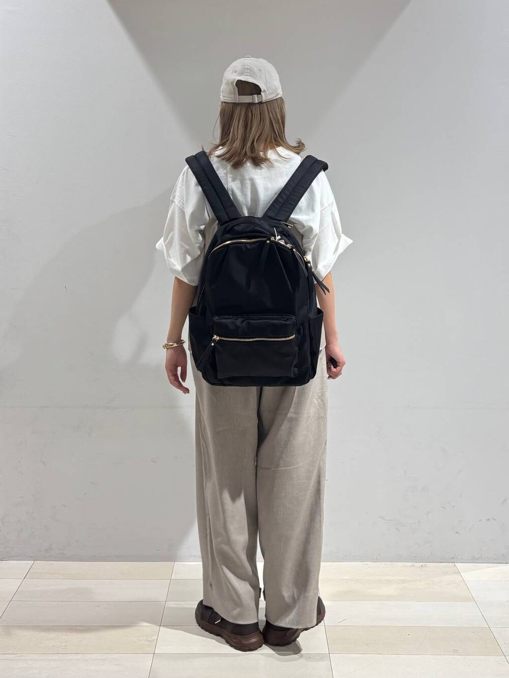 ブラウン系のスニーカー、ブラック系のバックパック/リュック、ベージュ系のサロペット/オーバーオールを着用したレディースの夏コーディネートの5枚目の写真