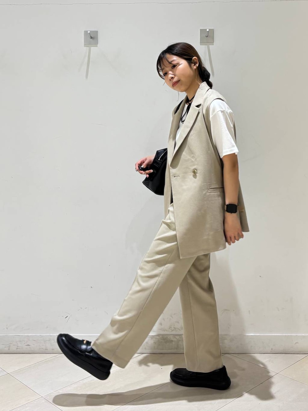 ブラック系のボストンバッグ、ベージュ系のその他パンツ、ベージュ系のベストを着用したレディースの春コーディネートの5枚目の写真