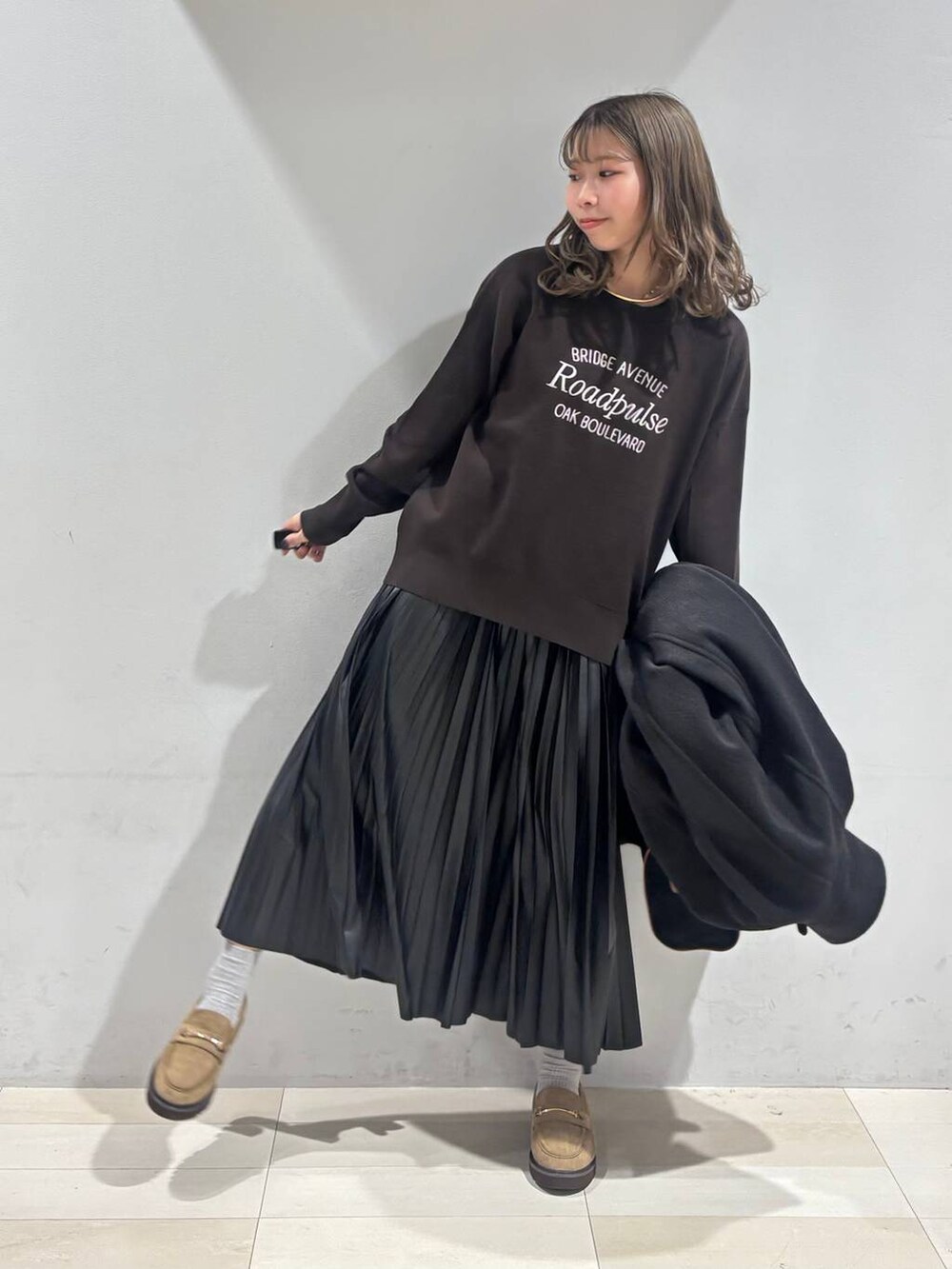 ブラック系のチェスターコート、ベージュ系のローファー、ブラック系のスカートを着用したレディースの秋コーディネートの7枚目の写真