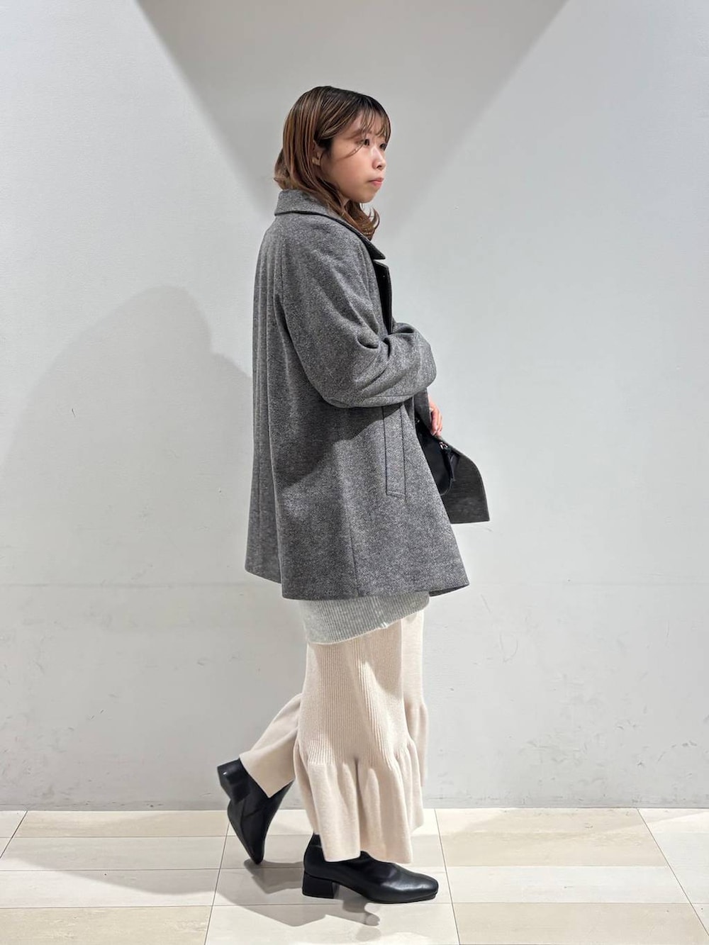 ブラック系のショルダーバッグ、グレー系のチェスターコート、グレー系のニット/セーターを着用したレディースの冬コーディネートの5枚目の写真