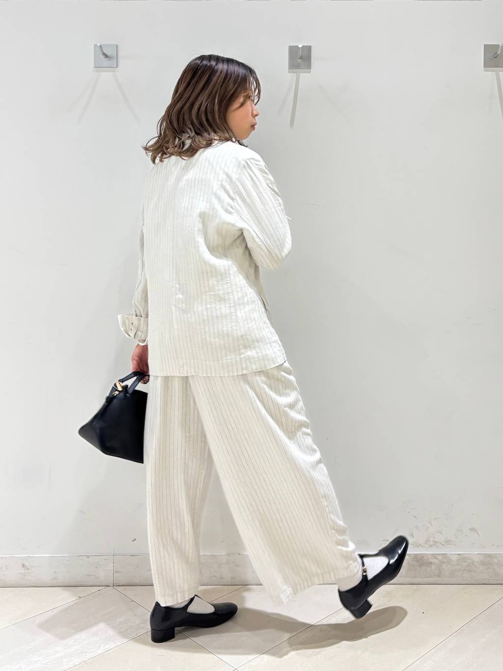 ブラック系のショルダーバッグ、ベージュ系のその他パンツ、グレー系のテーラードジャケットを着用したレディースの春コーディネートの6枚目の写真