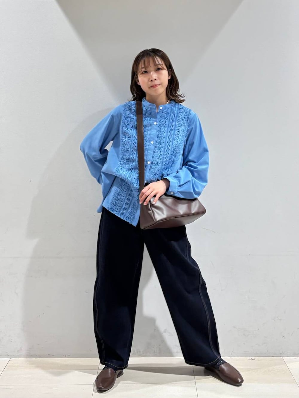 ブルー系のデニムパンツ、ブラウン系のショルダーバッグ、ブルー系のシャツ/ブラウスを着用したレディースの春コーディネートの2枚目の写真
