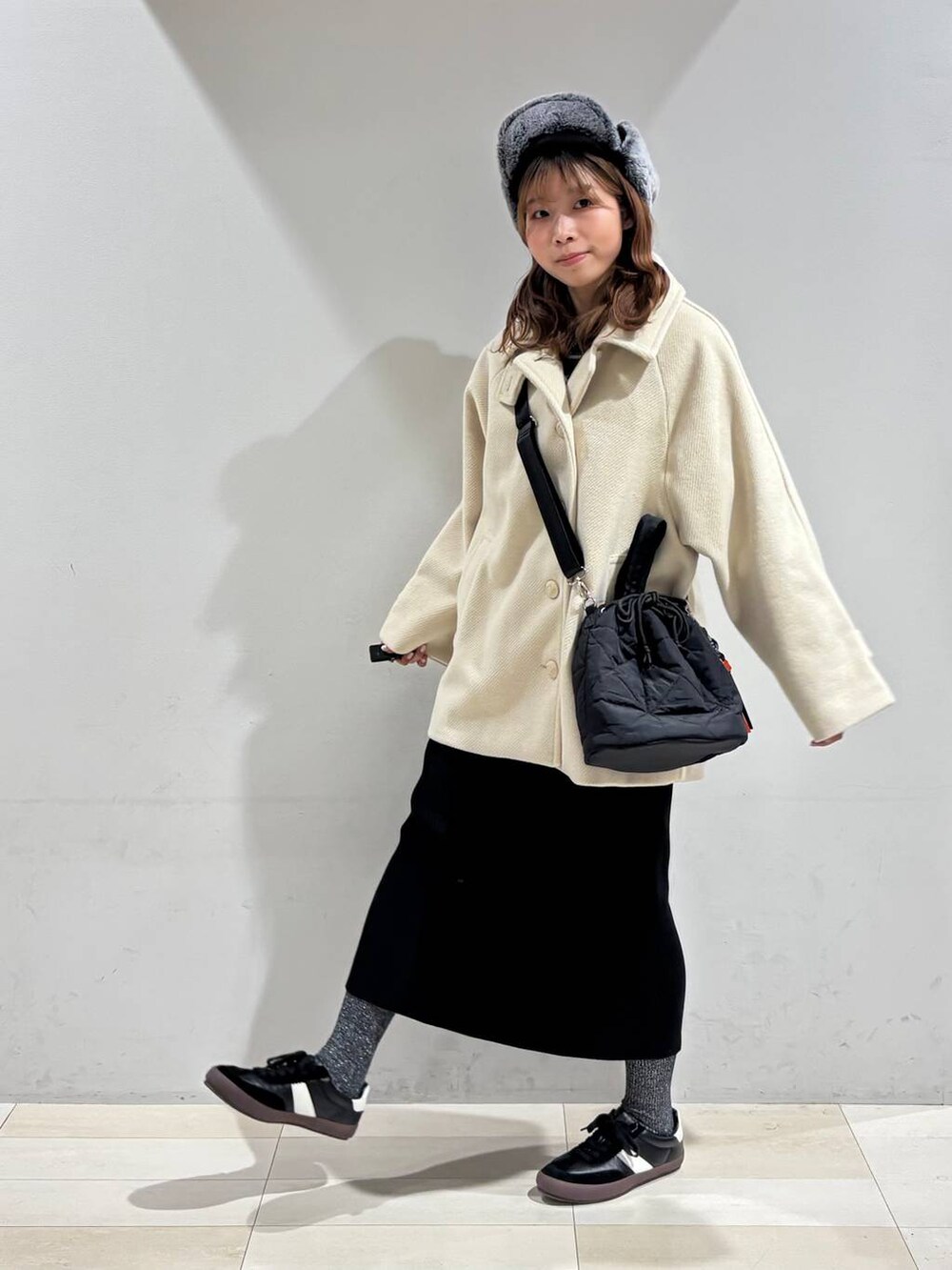 ブラック系のスニーカー、ブラック系のハンドバッグ、ブラック系のスカートを着用したレディースの冬コーディネートの9枚目の写真