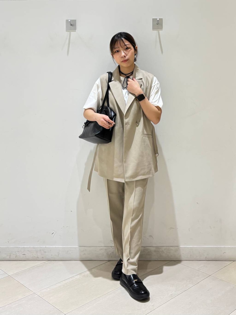 ブラック系のボストンバッグ、ベージュ系のその他パンツ、ベージュ系のベストを着用したレディースの春コーディネートの8枚目の写真