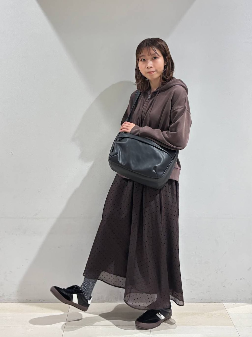 ブラック系のスニーカー、ブラック系のショルダーバッグ、ブラウン系のスカートを着用したレディースの春コーディネートの8枚目の写真
