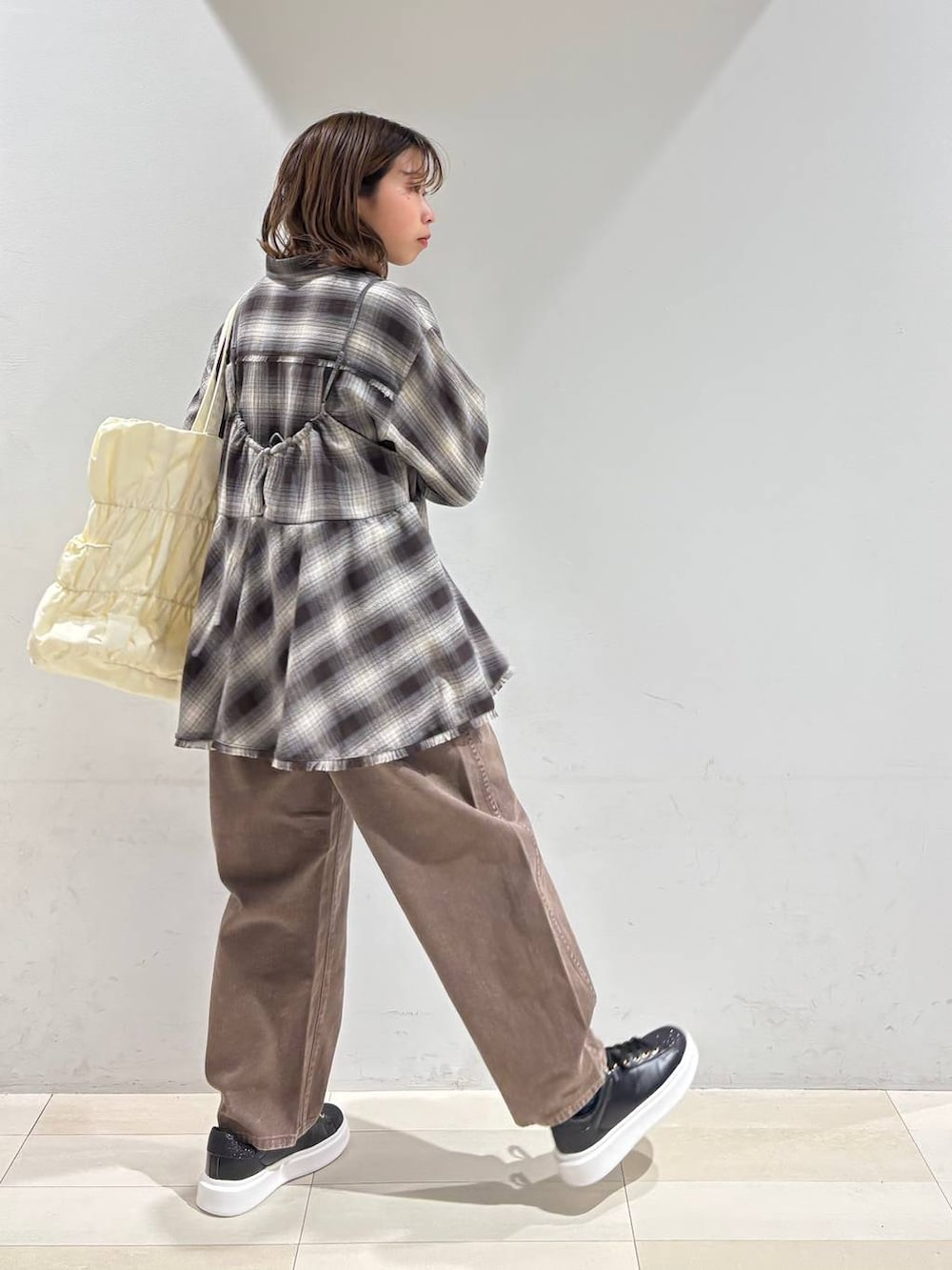 ベージュ系のトートバッグ、ブラウン系のデニムパンツ、ブラウン系のシャツ/ブラウスを着用したレディースの春コーディネートの6枚目の写真