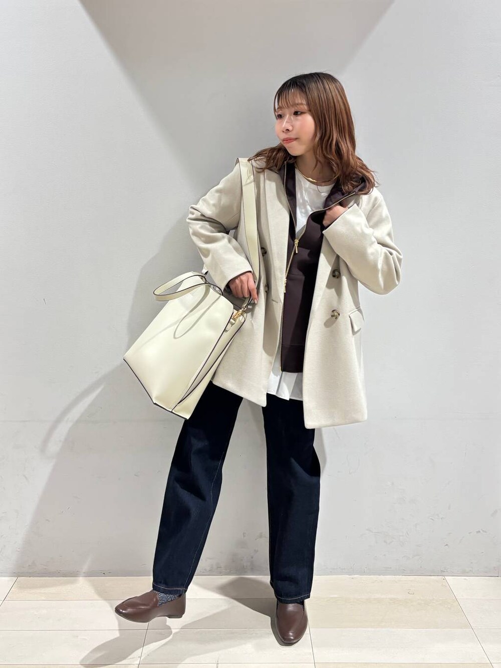 ホワイト系のトートバッグ、ブルー系のデニムパンツ、ベージュ系のテーラードジャケットを着用したレディースの冬コーディネートの9枚目の写真