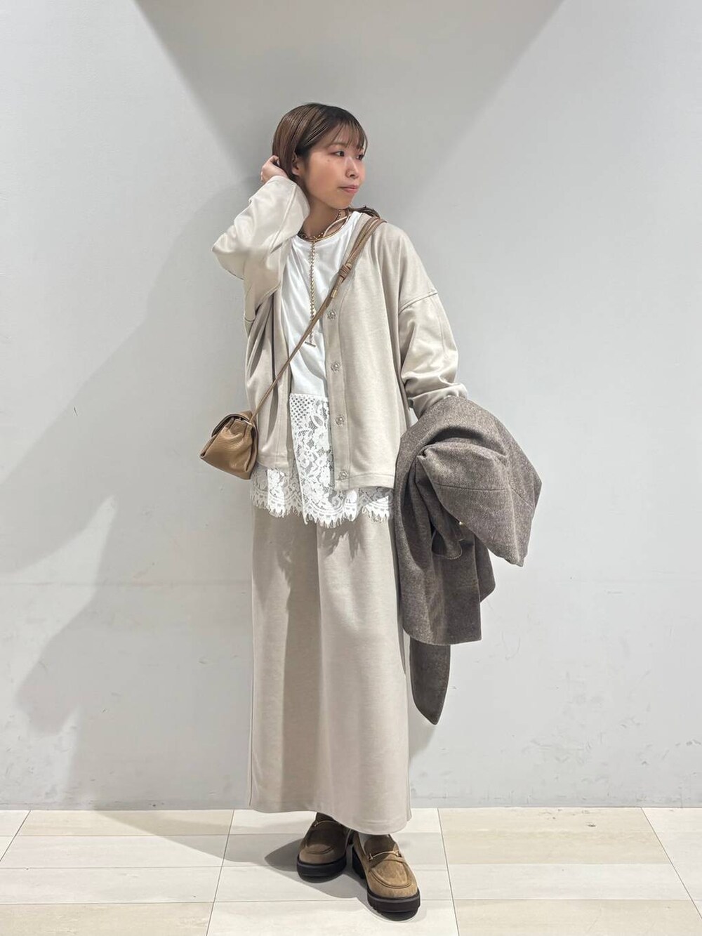 ブラウン系のチェスターコート、ベージュ系のローファー、ベージュ系のショルダーバッグを着用したレディースの秋コーディネートの9枚目の写真