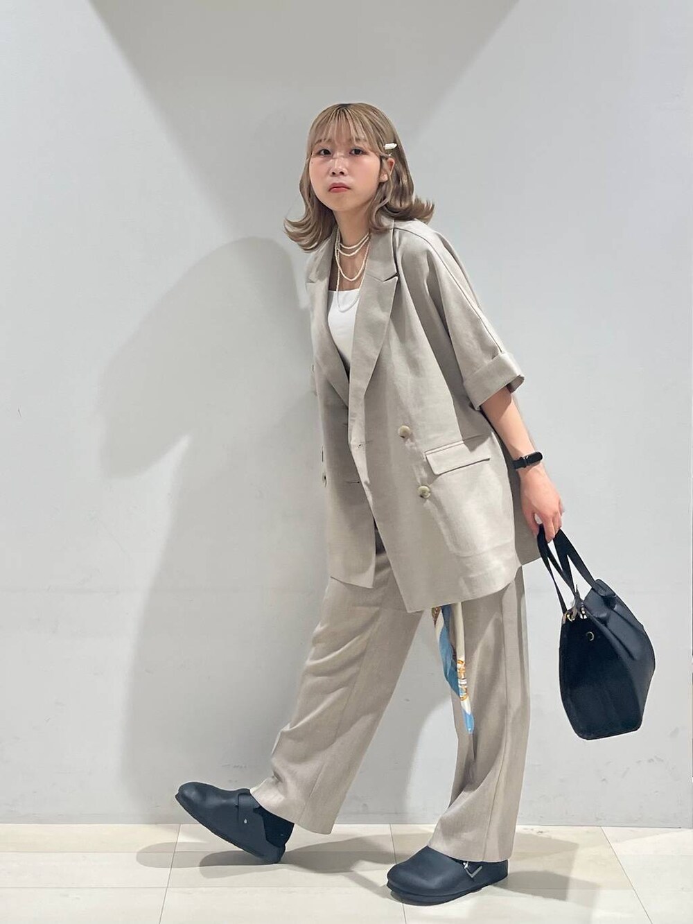 ブラック系のショルダーバッグ、ホワイト系のキャミソール、ブラック系のサンダルを着用したレディースの夏コーディネートの2枚目の写真