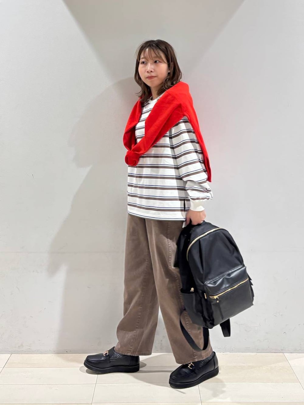 ブラック系のローファー、ブラック系のバックパック/リュック、ブラウン系のデニムパンツを着用したレディースの春コーディネートの4枚目の写真