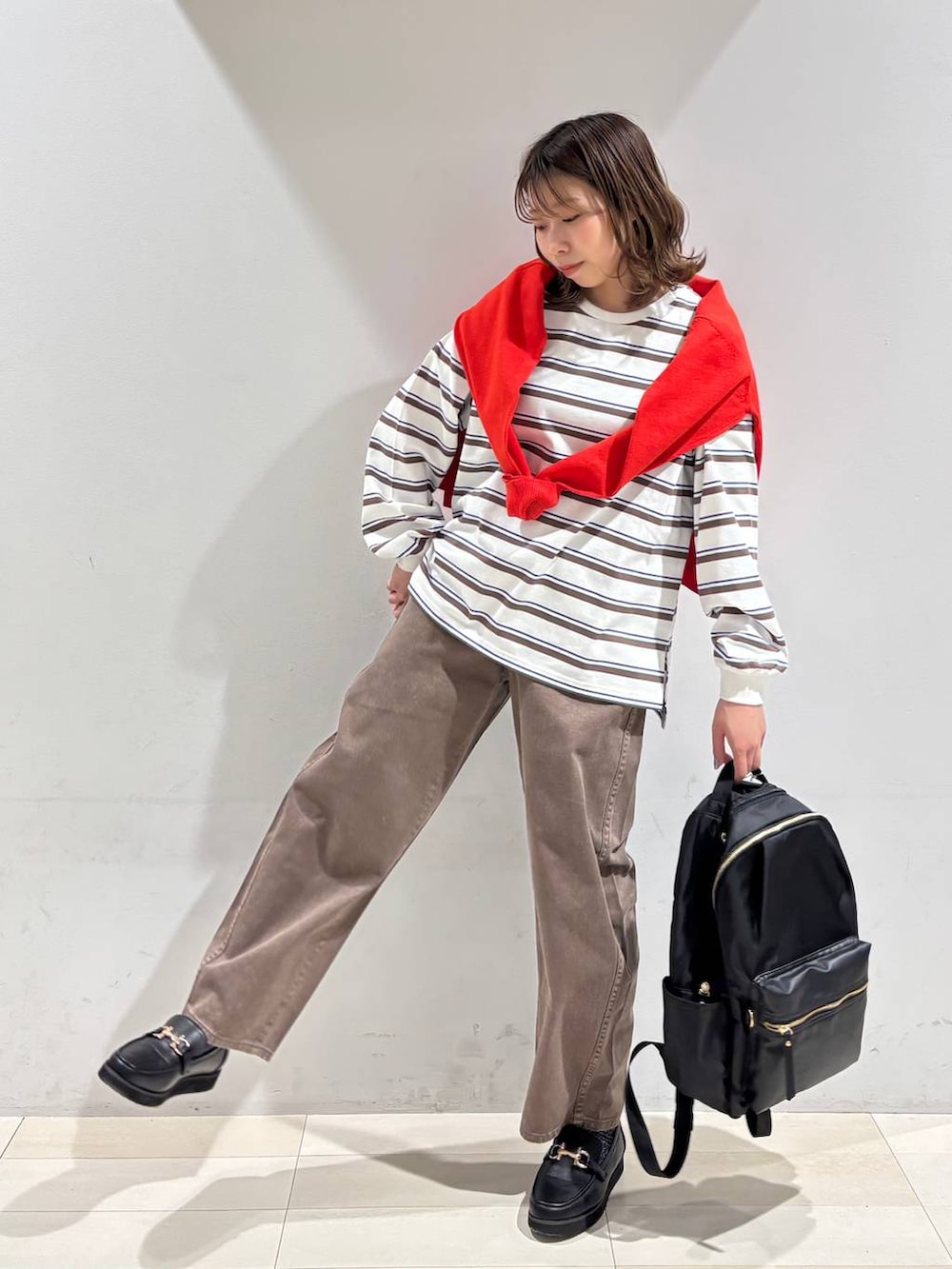 ブラック系のローファー、ブラック系のバックパック/リュック、ブラウン系のデニムパンツを着用したレディースの春コーディネートの6枚目の写真