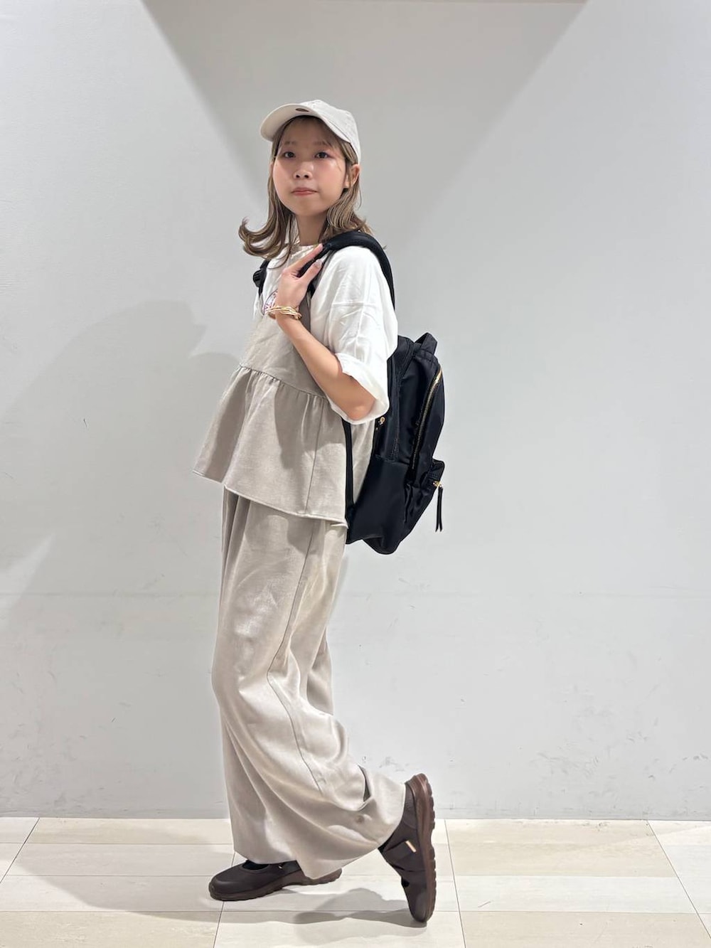 ブラウン系のスニーカー、ブラック系のバックパック/リュック、ベージュ系のサロペット/オーバーオールを着用したレディースの夏コーディネートの4枚目の写真