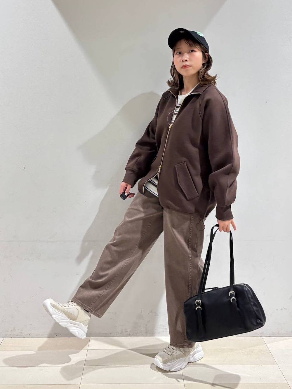 ブラウン系のデニムパンツ、ブラウン系のブルゾン、ゴールド系のスニーカーを着用したレディースの春コーディネートの3枚目の写真