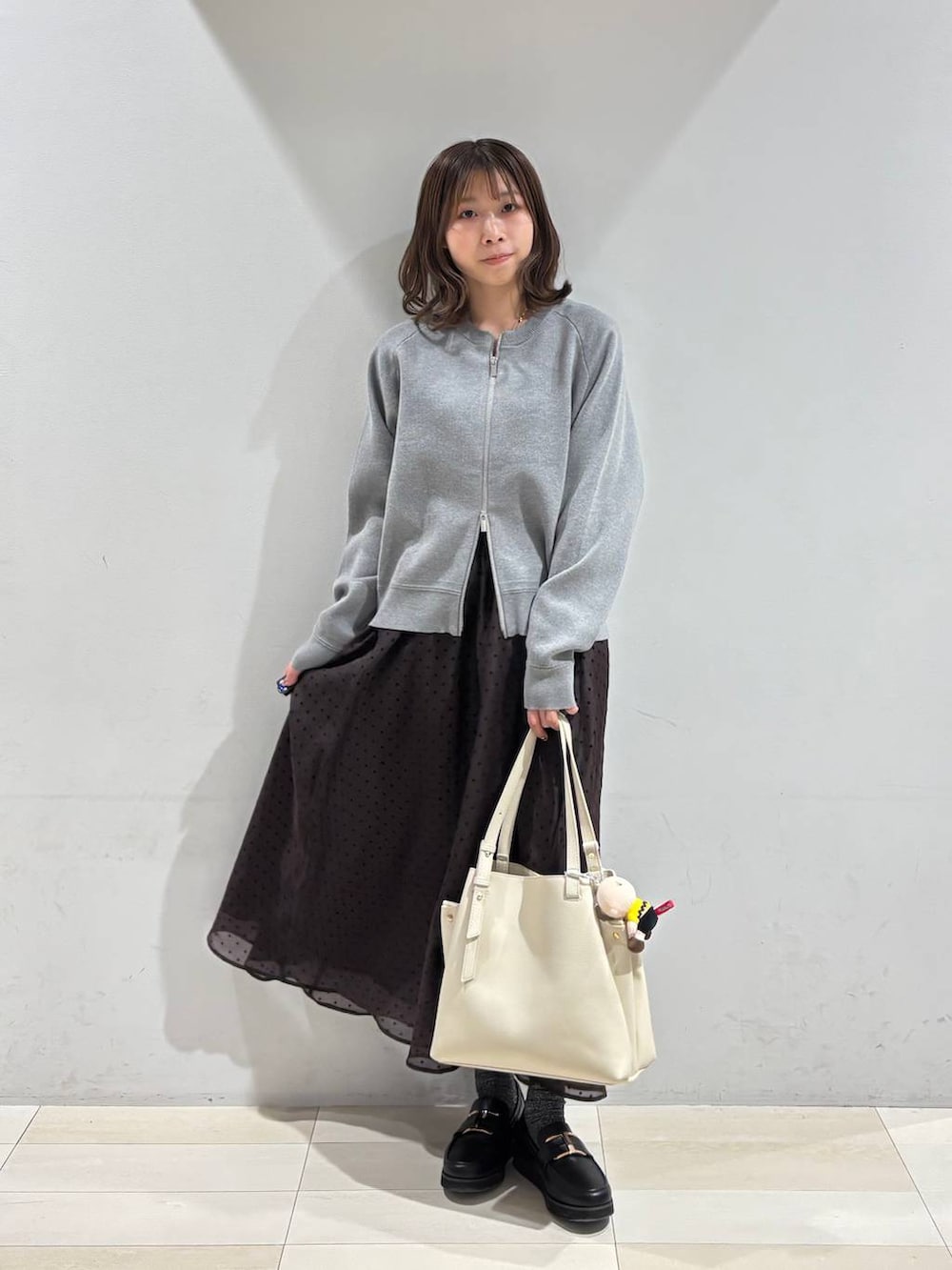 ブラック系のローファー、ホワイト系のハンドバッグ、ブラウン系のスカートを着用したレディースの春コーディネートの9枚目の写真