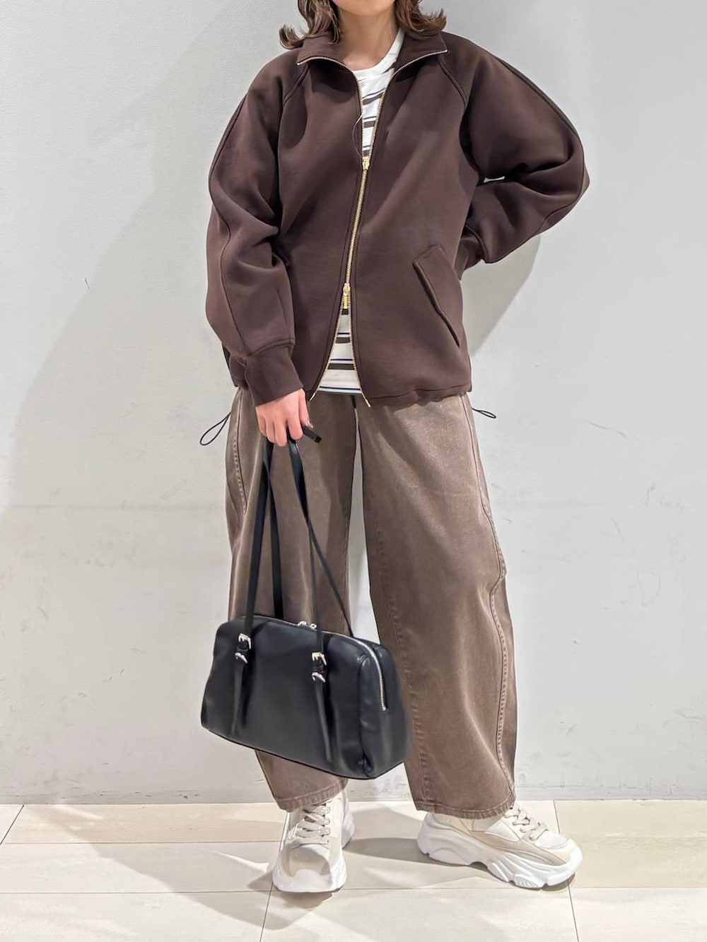 ブラウン系のデニムパンツ、ブラウン系のブルゾン、ゴールド系のスニーカーを着用したレディースの春コーディネートの2枚目の写真