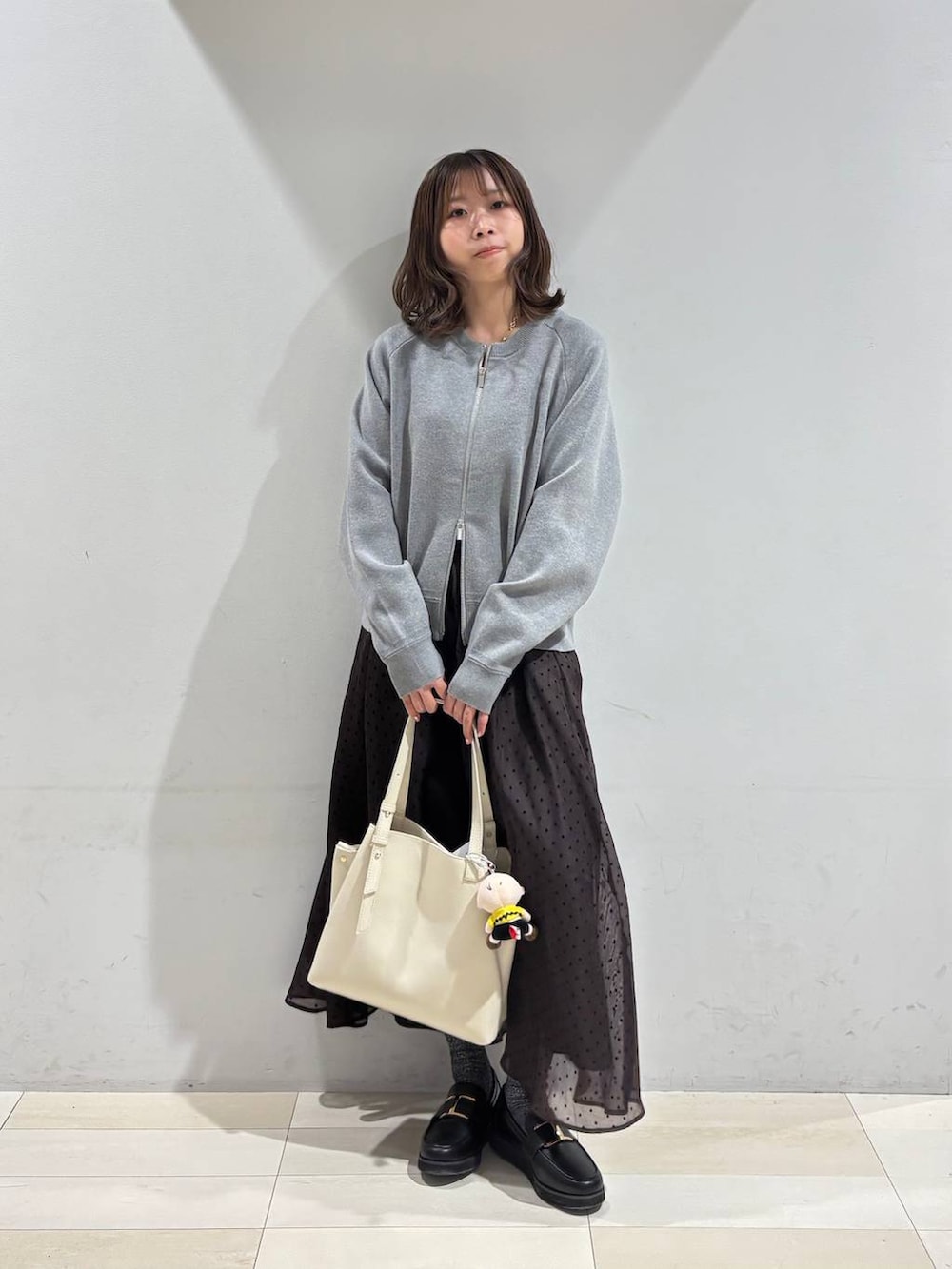 ブラック系のローファー、ホワイト系のハンドバッグ、ブラウン系のスカートを着用したレディースの春コーディネートの8枚目の写真