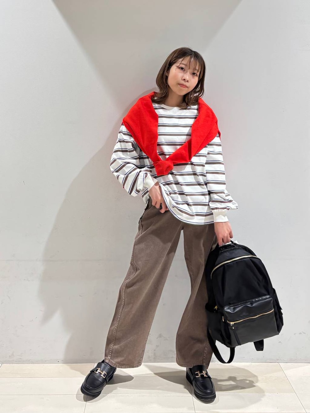 ブラック系のローファー、ブラック系のバックパック/リュック、ブラウン系のデニムパンツを着用したレディースの春コーディネートの7枚目の写真