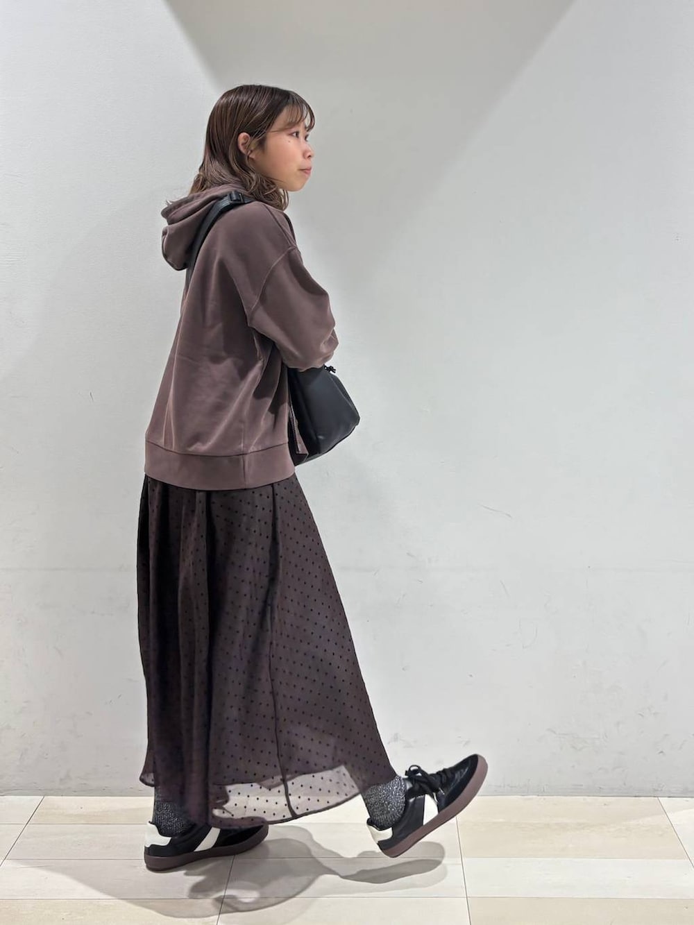 ブラック系のスニーカー、ブラック系のショルダーバッグ、ブラウン系のスカートを着用したレディースの春コーディネートの5枚目の写真