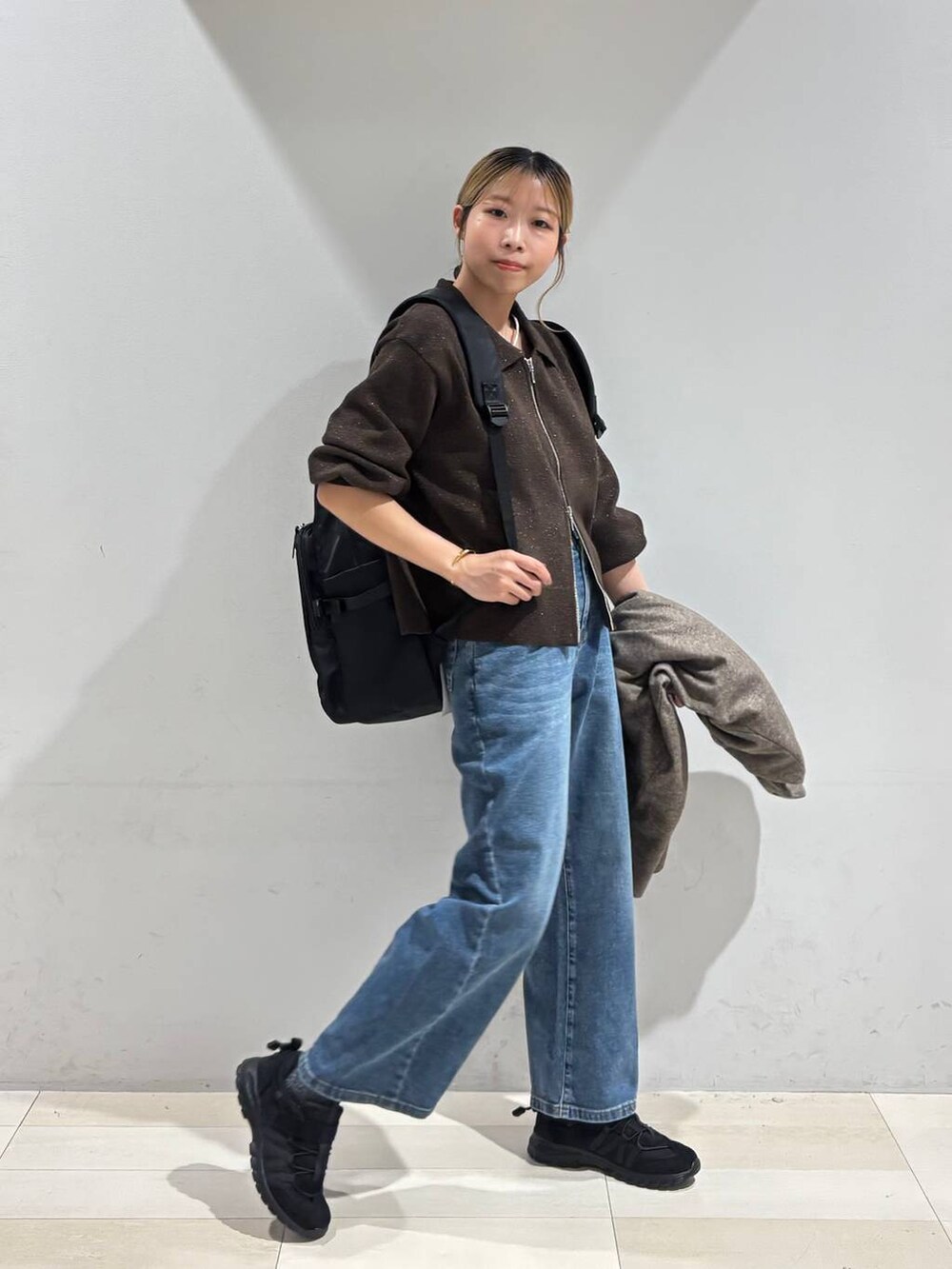 ブラック系のバックパック/リュック、ブラウン系のチェスターコート、ブラウン系のワンピースを着用したレディースの秋コーディネートの2枚目の写真