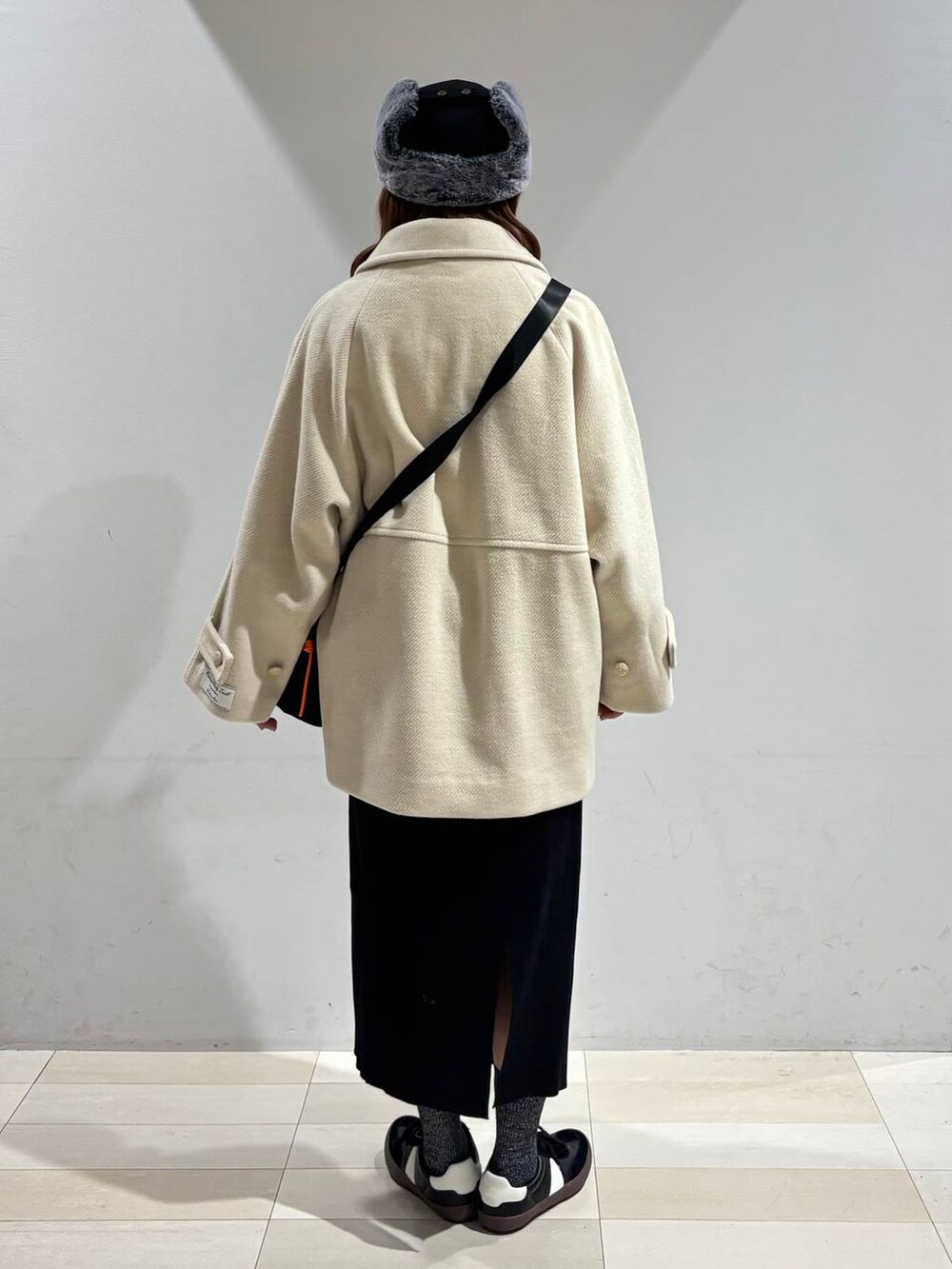 ブラック系のスニーカー、ブラック系のハンドバッグ、ブラック系のスカートを着用したレディースの冬コーディネートの6枚目の写真