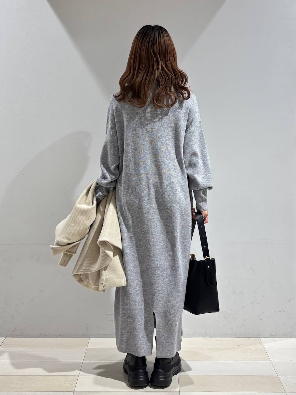 ブラック系のショルダーバッグ、グレー系のワンピース、ブラック系のブーツを着用したレディースの冬コーディネートの8枚目の写真