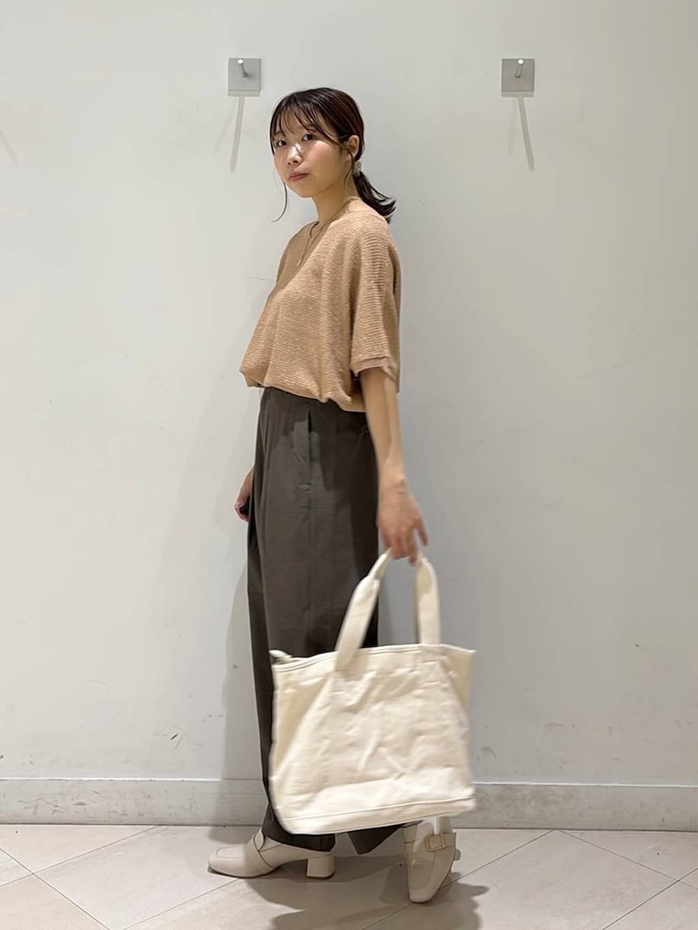 ベージュ系のローファー、ホワイト系のトートバッグ、オレンジ系のニット/セーターを着用したレディースの春コーディネートの5枚目の写真
