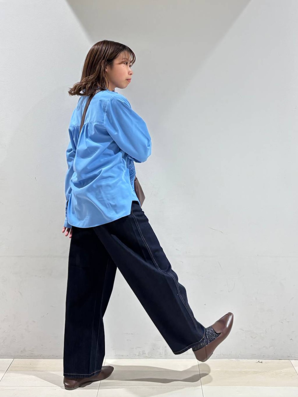 ブルー系のデニムパンツ、ブラウン系のショルダーバッグ、ブルー系のシャツ/ブラウスを着用したレディースの春コーディネートの6枚目の写真