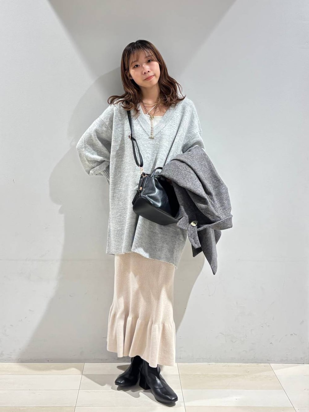 ブラック系のショルダーバッグ、グレー系のチェスターコート、グレー系のニット/セーターを着用したレディースの冬コーディネートの7枚目の写真