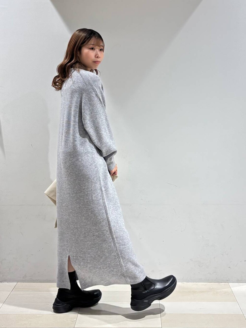 ブラック系のショルダーバッグ、グレー系のワンピース、ブラック系のブーツを着用したレディースの冬コーディネートの7枚目の写真