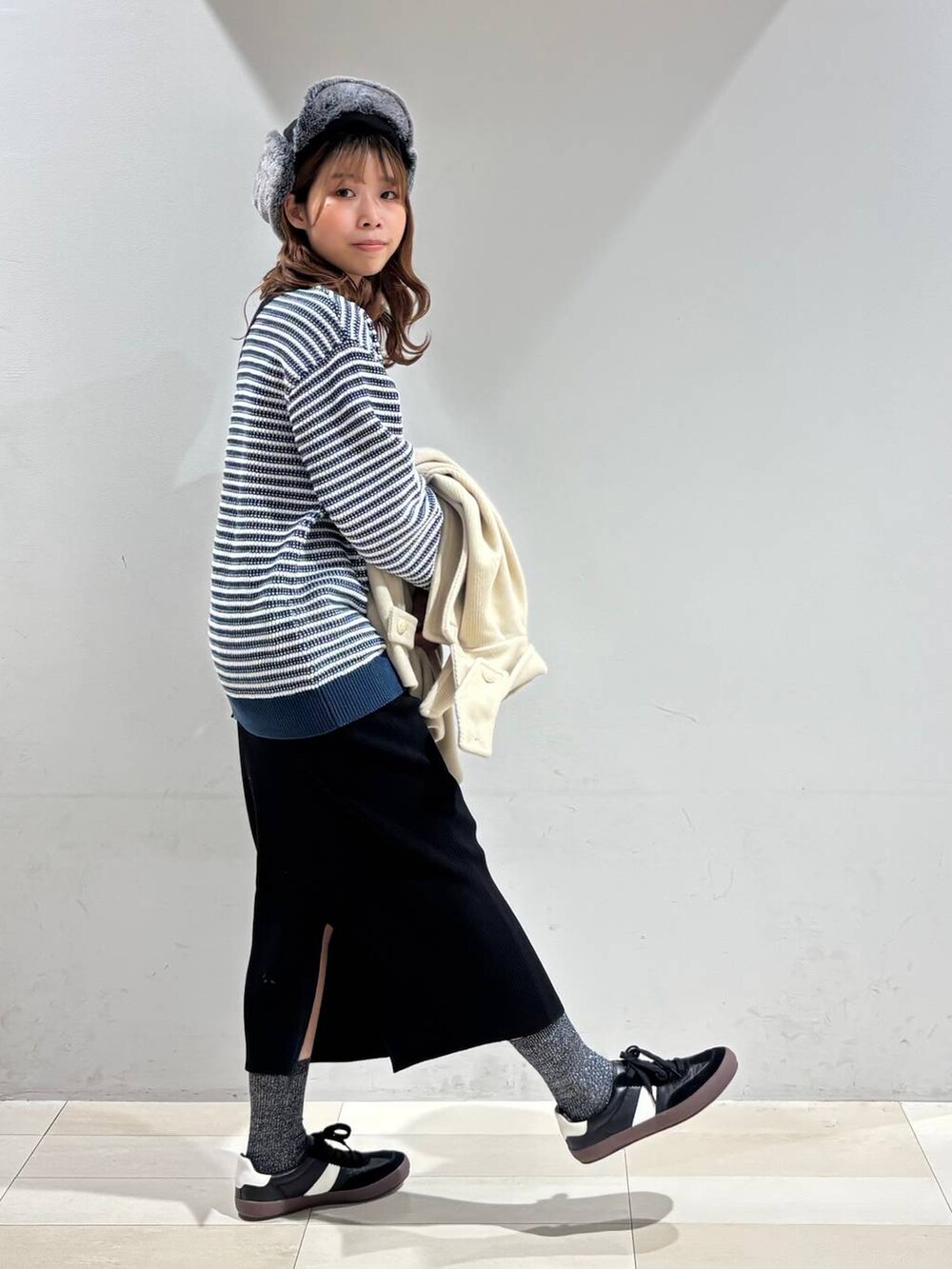 ブラック系のスニーカー、ブラック系のハンドバッグ、ブラック系のスカートを着用したレディースの冬コーディネートの3枚目の写真