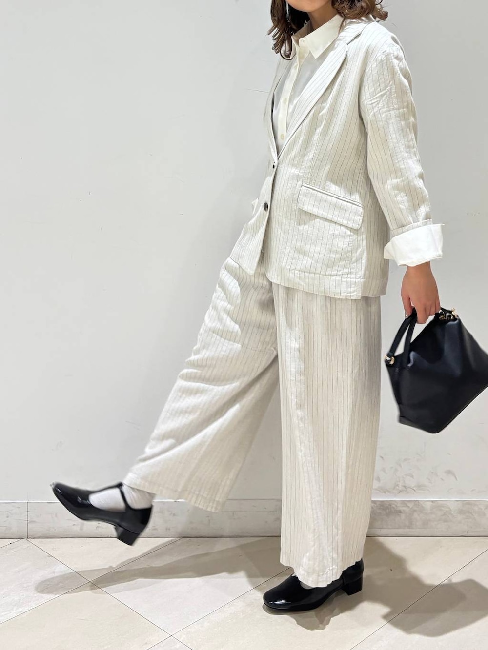 ブラック系のショルダーバッグ、ベージュ系のその他パンツ、グレー系のテーラードジャケットを着用したレディースの春コーディネートの3枚目の写真