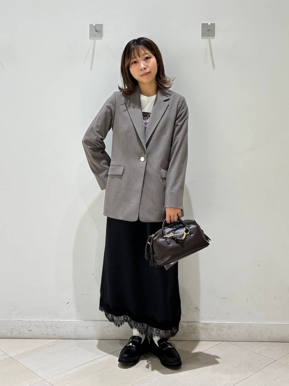ブラック系のローファー、ブラウン系のテーラードジャケット、ブラウン系のボストンバッグを着用したレディースの春コーディネートの2枚目の写真