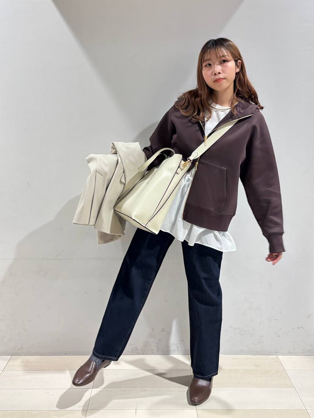 ホワイト系のトートバッグ、ブルー系のデニムパンツ、ベージュ系のテーラードジャケットを着用したレディースの冬コーディネートの3枚目の写真