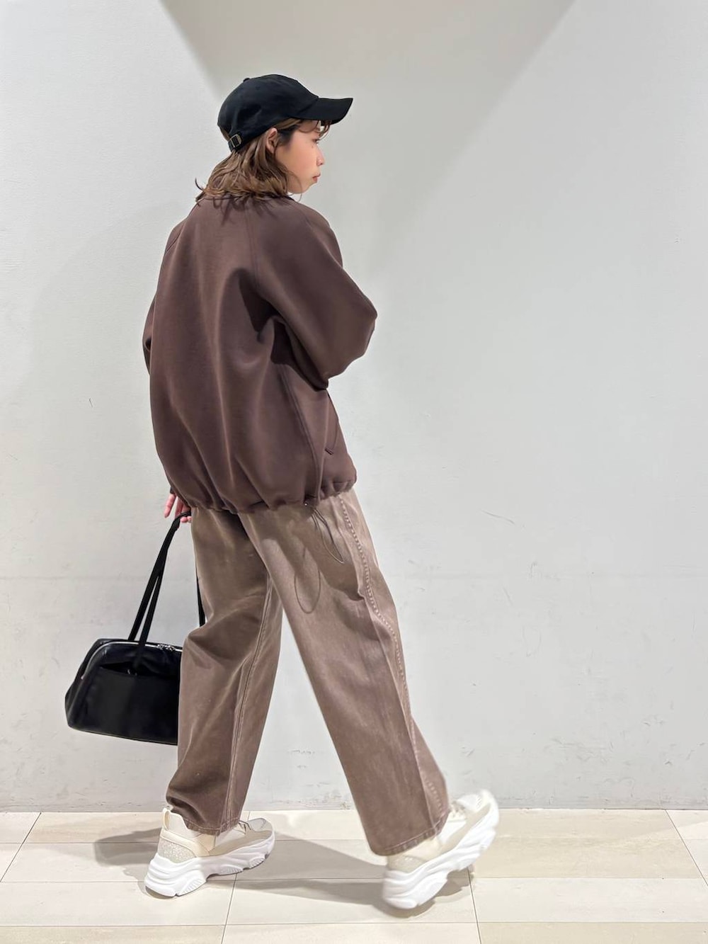 ブラウン系のデニムパンツ、ブラウン系のブルゾン、ゴールド系のスニーカーを着用したレディースの春コーディネートの5枚目の写真