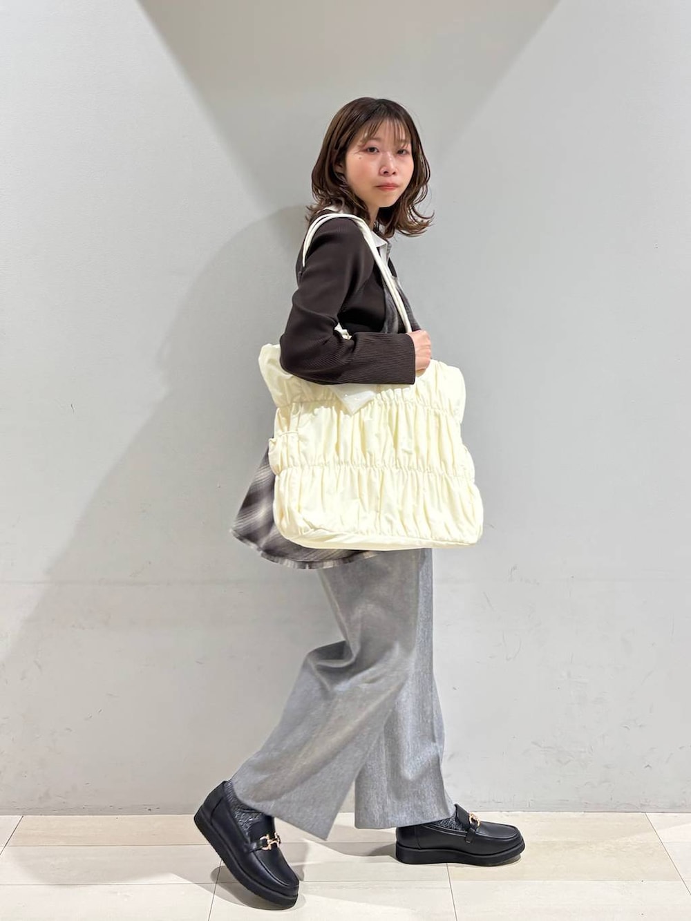 ブラック系のローファー、ベージュ系のトートバッグ、グレー系のその他パンツを着用したレディースの春コーディネートの4枚目の写真