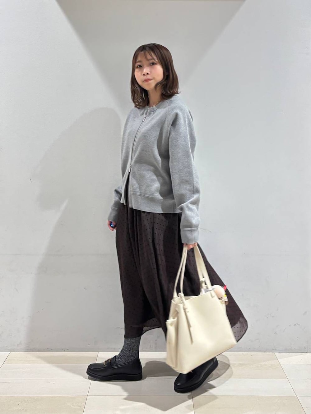 ブラック系のローファー、ホワイト系のハンドバッグ、ブラウン系のスカートを着用したレディースの春コーディネートの3枚目の写真