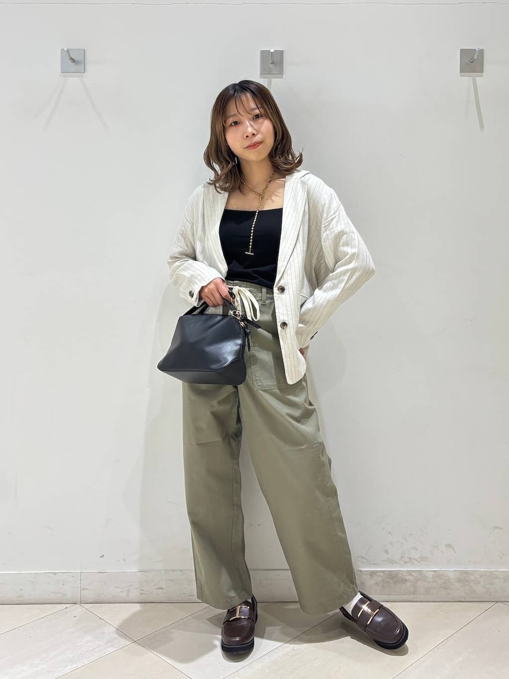 ブラック系のショルダーバッグ、ブラウン系のローファー、ブラック系のキャミソールを着用したレディースの春コーディネートの2枚目の写真