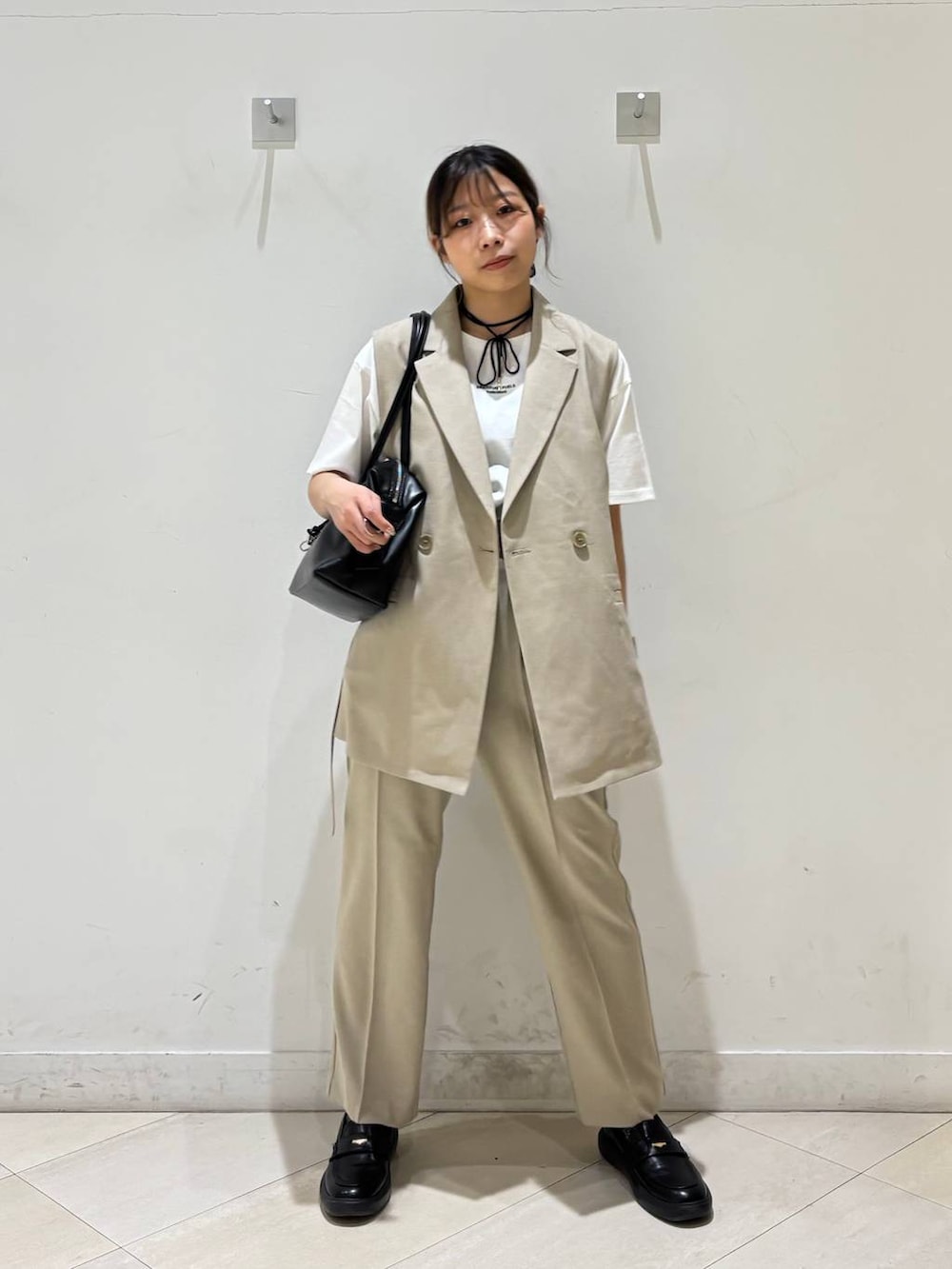 ブラック系のボストンバッグ、ベージュ系のその他パンツ、ベージュ系のベストを着用したレディースの春コーディネートの7枚目の写真