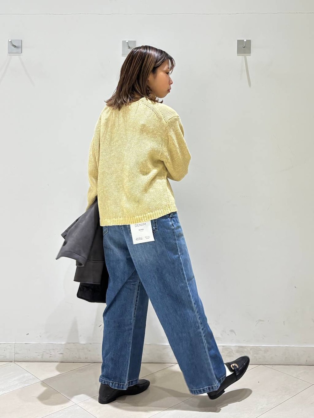 ブラック系のローファー、ブラック系のトートバッグ、ブルー系のデニムパンツを着用したレディースの春コーディネートの5枚目の写真