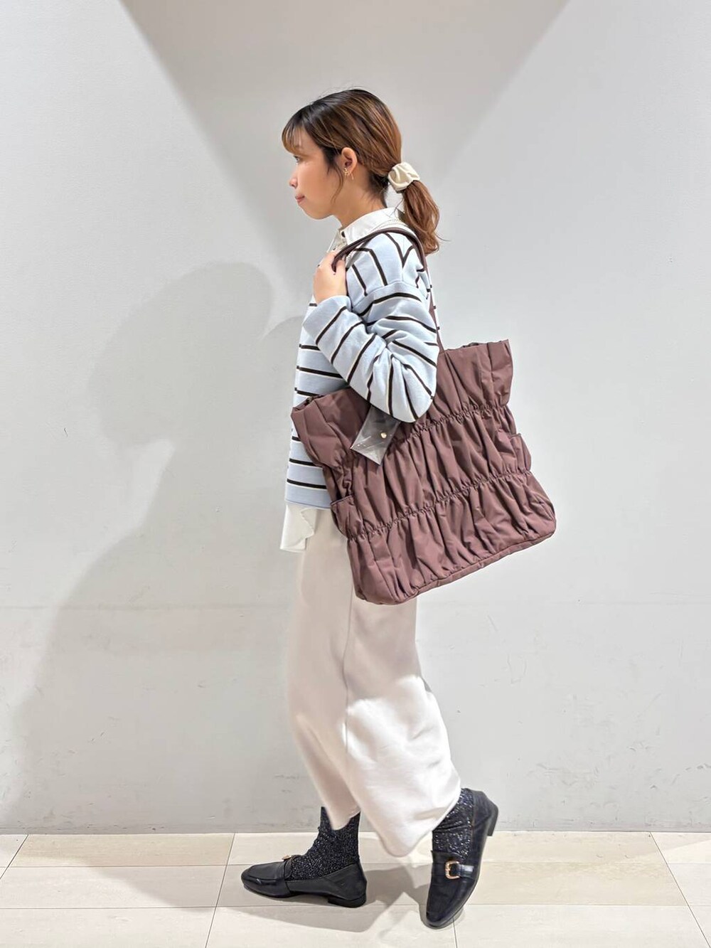 ブラック系のローファー、ブラウン系のトートバッグ、ブルー系のニット/セーターを着用したレディースの冬コーディネートの4枚目の写真