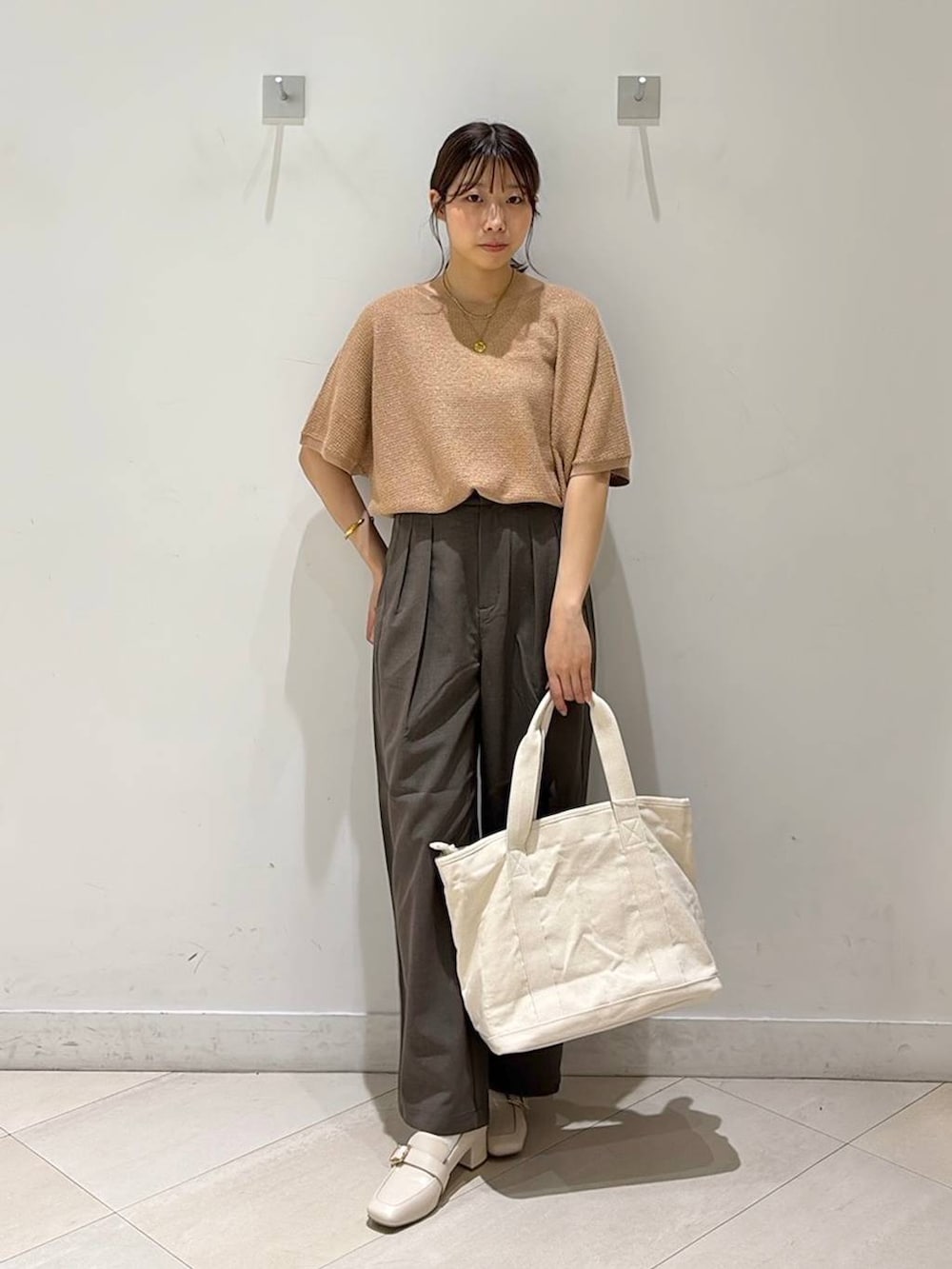 ベージュ系のローファー、ホワイト系のトートバッグ、オレンジ系のニット/セーターを着用したレディースの春コーディネートの3枚目の写真