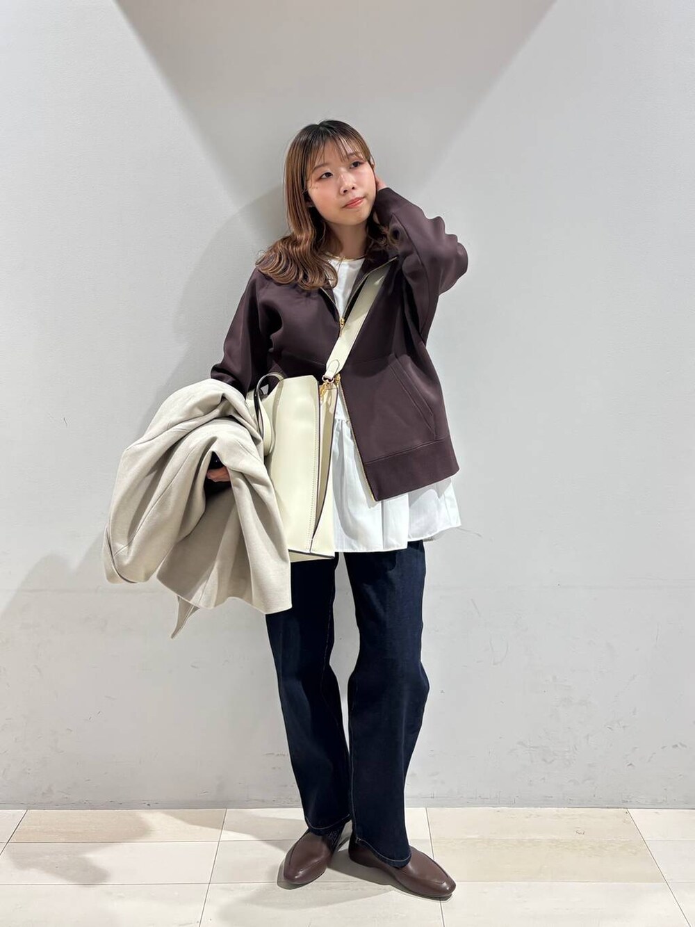 ホワイト系のトートバッグ、ブルー系のデニムパンツ、ベージュ系のテーラードジャケットを着用したレディースの冬コーディネートの2枚目の写真