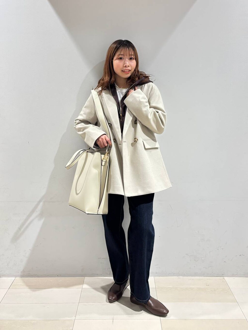 ホワイト系のトートバッグ、ブルー系のデニムパンツ、ベージュ系のテーラードジャケットを着用したレディースの冬コーディネートの5枚目の写真