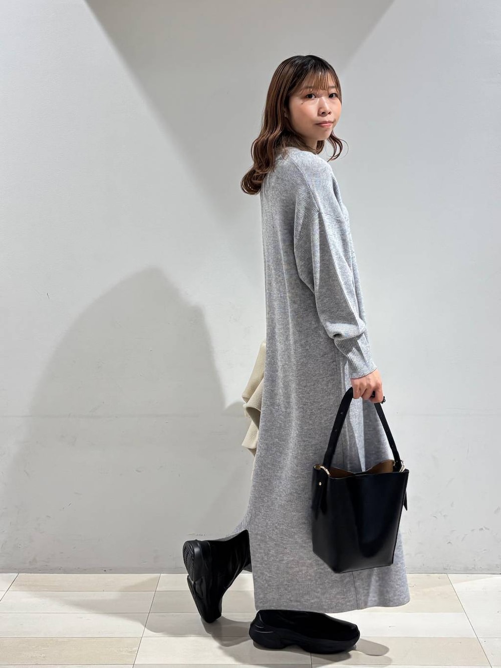 ブラック系のショルダーバッグ、グレー系のワンピース、ブラック系のブーツを着用したレディースの冬コーディネートの6枚目の写真