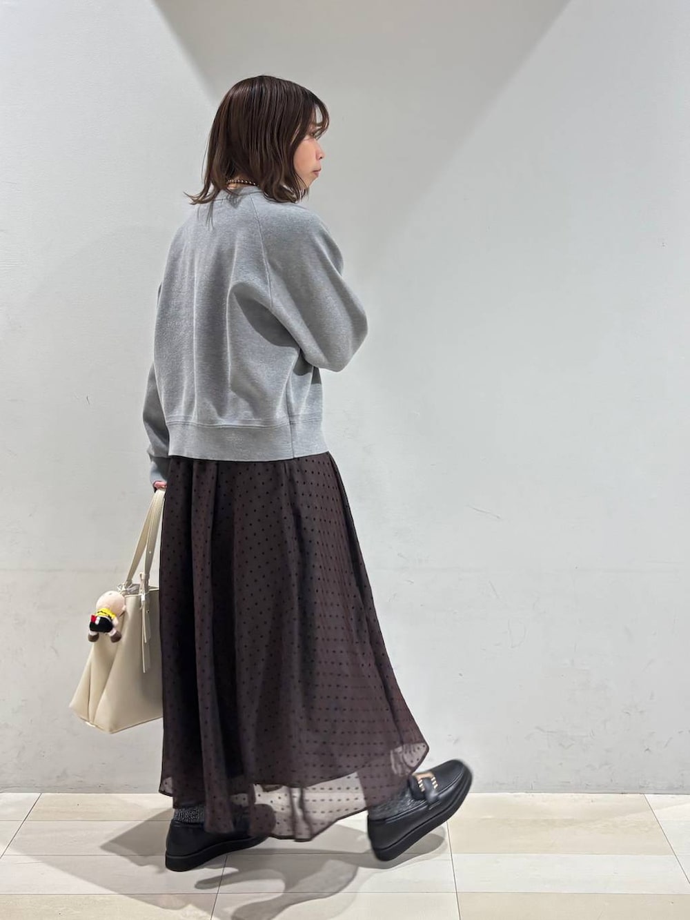 ブラック系のローファー、ホワイト系のハンドバッグ、ブラウン系のスカートを着用したレディースの春コーディネートの5枚目の写真